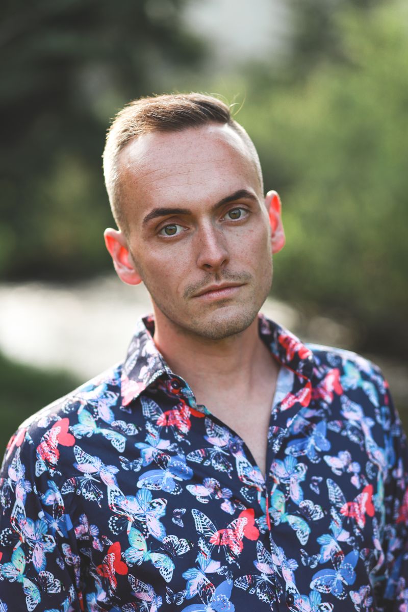 Tyler standing by a creek, looking calmly toward the camera