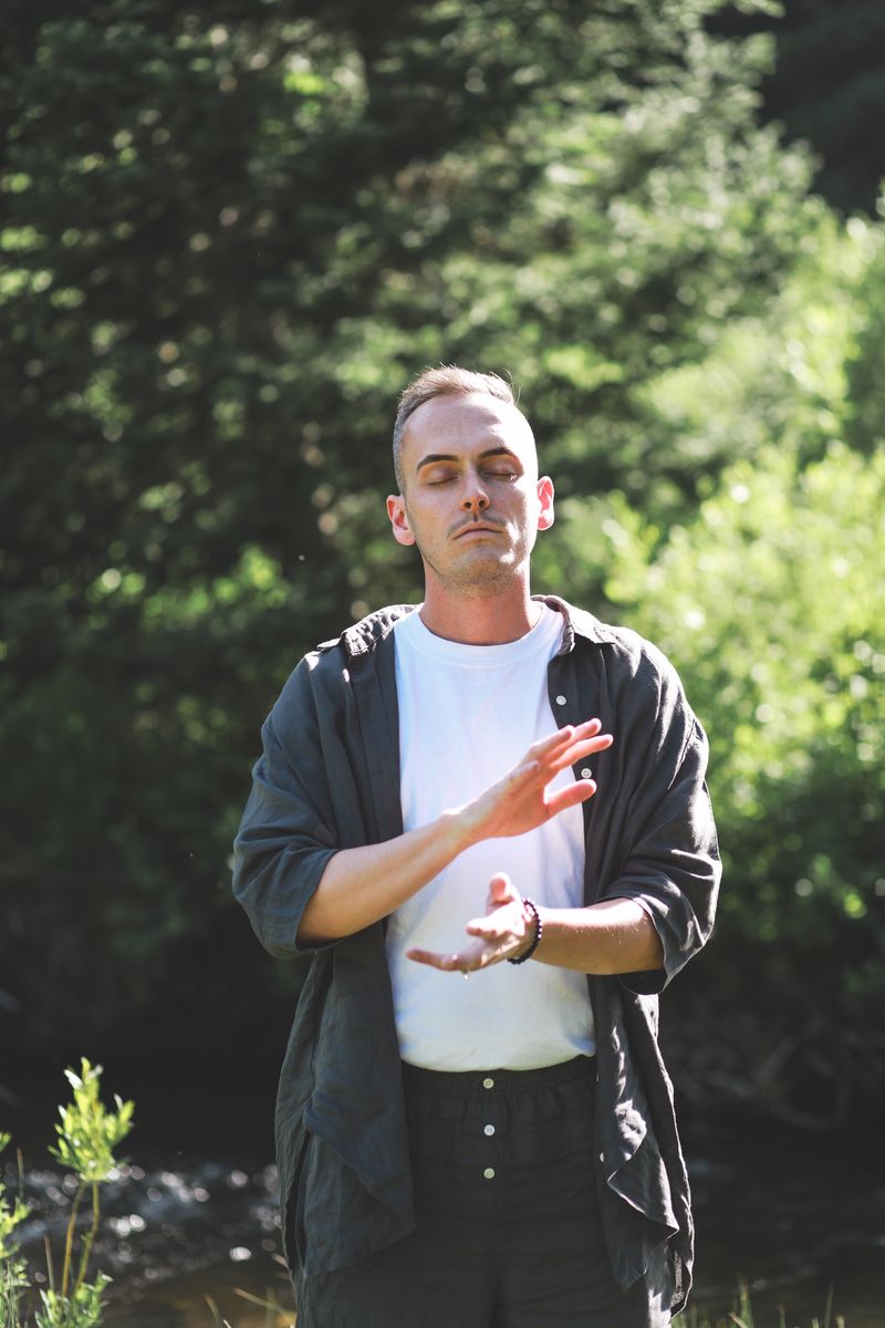 Tyler standing among pine trees, hands together