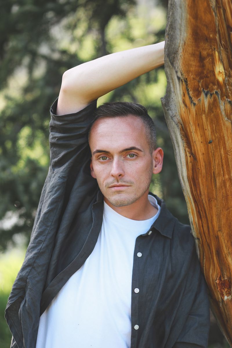 Tyler leaning against a tree trunk
