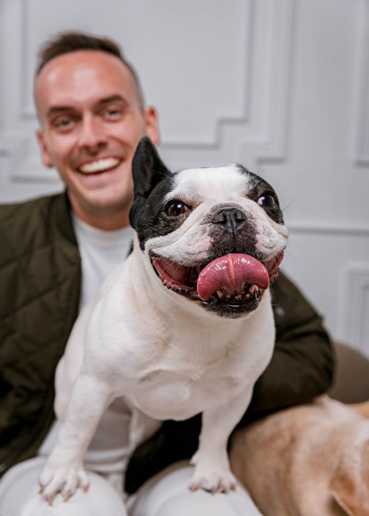Tyler laughing as he holds a French Bulldog on his lap