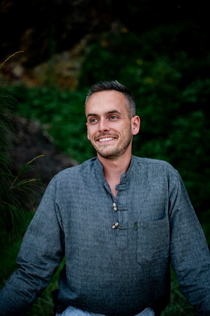 Tyler smiling outdoors in a blue linen shirt